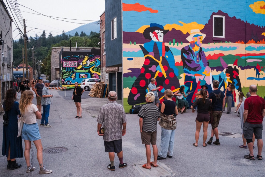 A group of people gathered in front of a colourful mural
