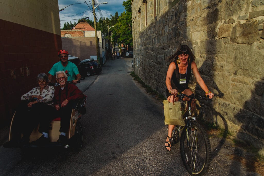 Amber Santos rides a bike next to a Cycling Without Age Trishaw